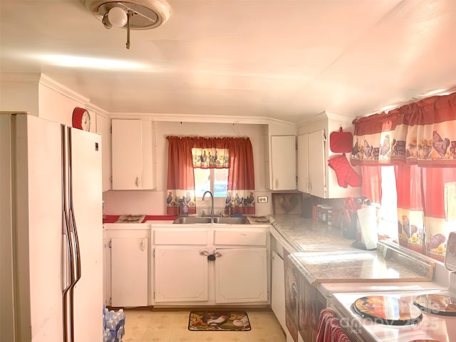 kitchen featuring white fridge, sink, white cabinets, and stove