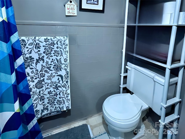 bathroom featuring toilet and tile walls