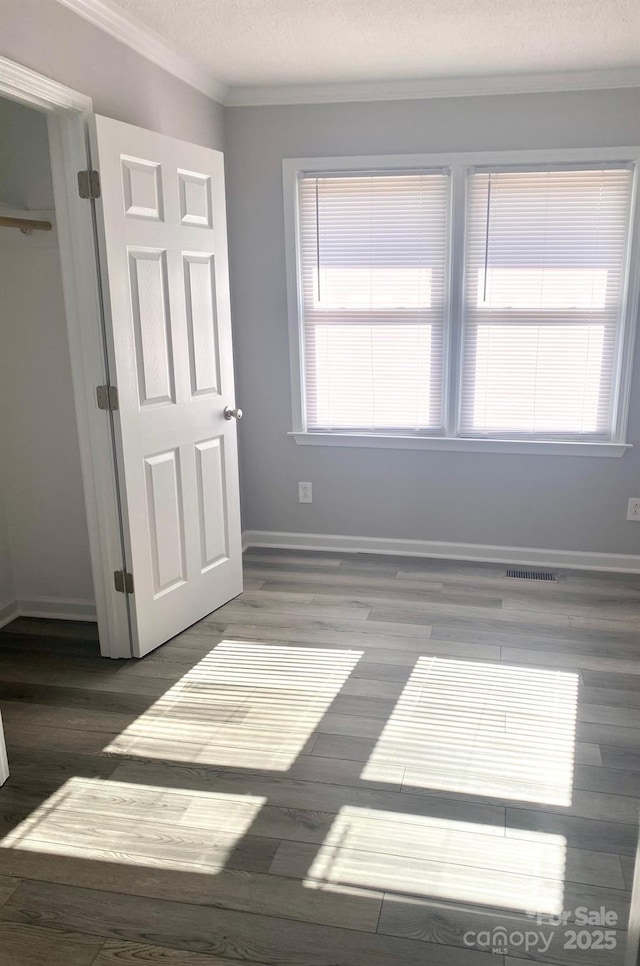 bedroom with a textured ceiling, a closet, crown molding, and dark hardwood / wood-style floors