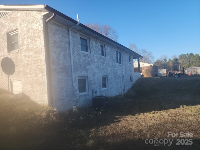 view of side of property with central AC and brick siding