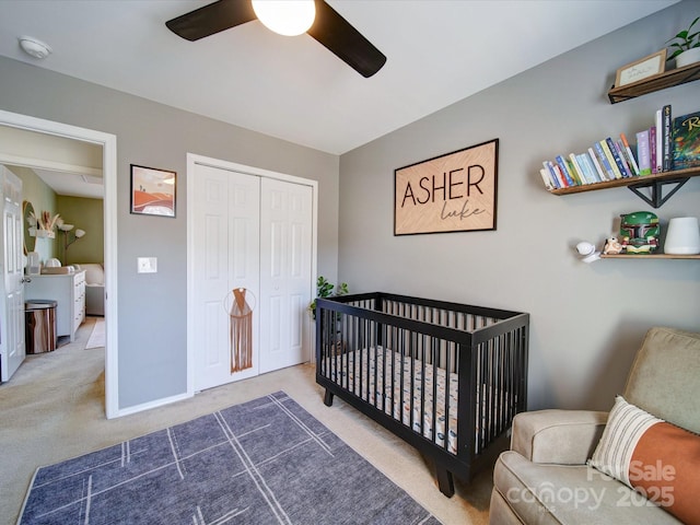 carpeted bedroom featuring ceiling fan, a crib, and a closet