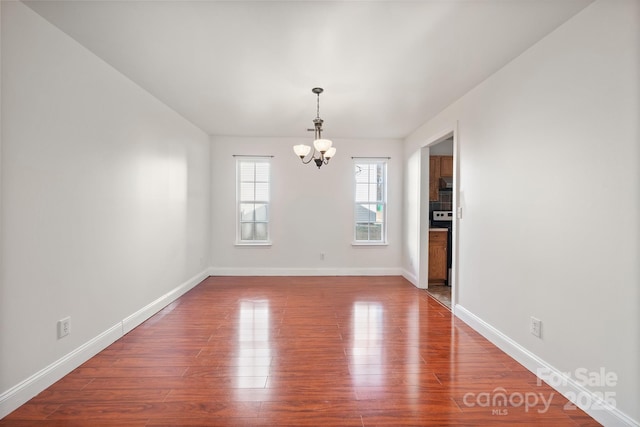 unfurnished dining area featuring a chandelier and hardwood / wood-style flooring