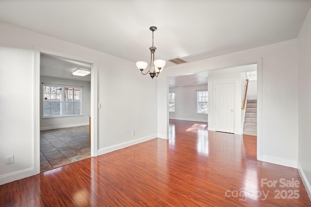 spare room with a chandelier and wood-type flooring