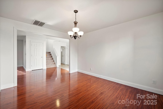 empty room featuring dark wood-type flooring and a chandelier