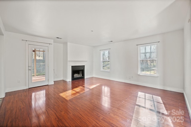 unfurnished living room featuring wood-type flooring and a healthy amount of sunlight