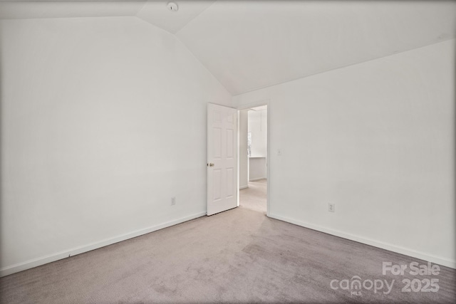 empty room featuring carpet and vaulted ceiling