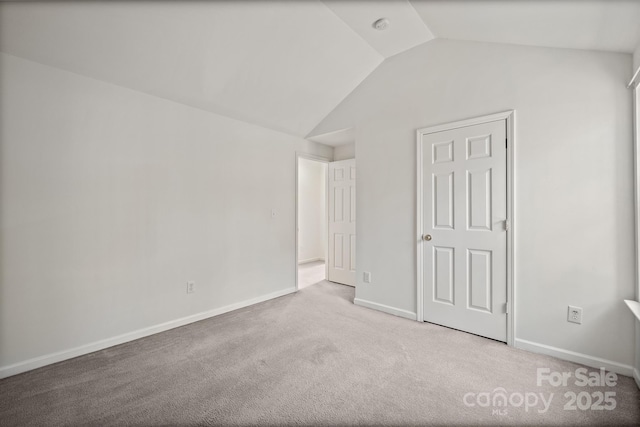 carpeted spare room featuring vaulted ceiling