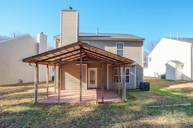 rear view of property featuring a patio area, central air condition unit, a storage shed, and a lawn