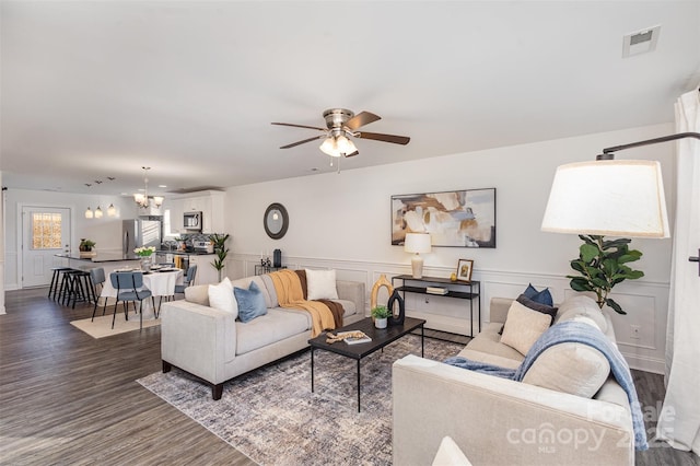 living room featuring ceiling fan with notable chandelier and dark hardwood / wood-style floors