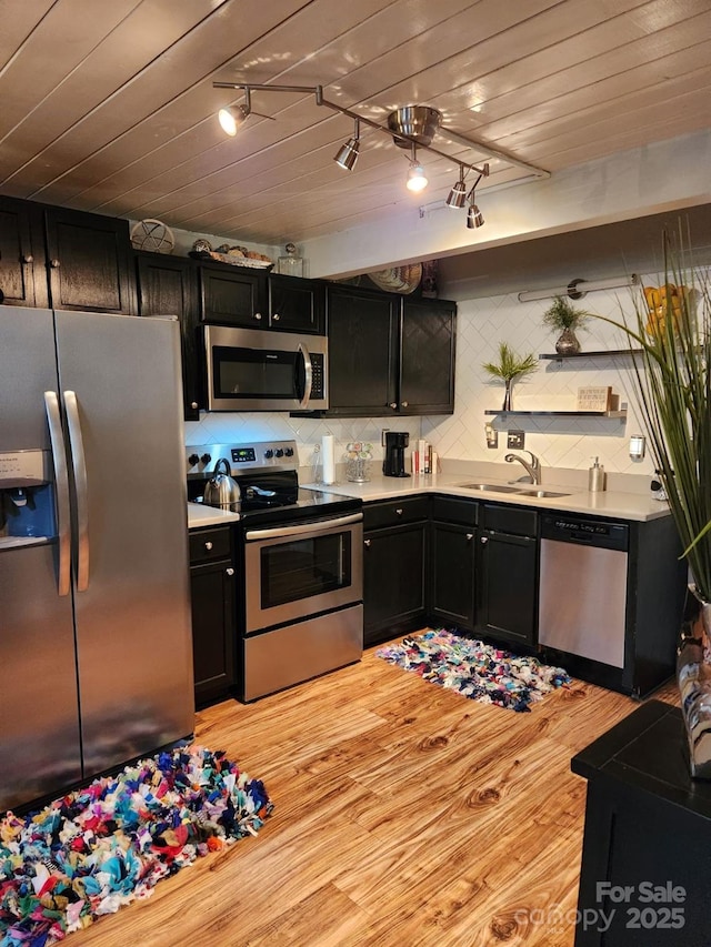 kitchen with light hardwood / wood-style floors, wood ceiling, backsplash, appliances with stainless steel finishes, and sink