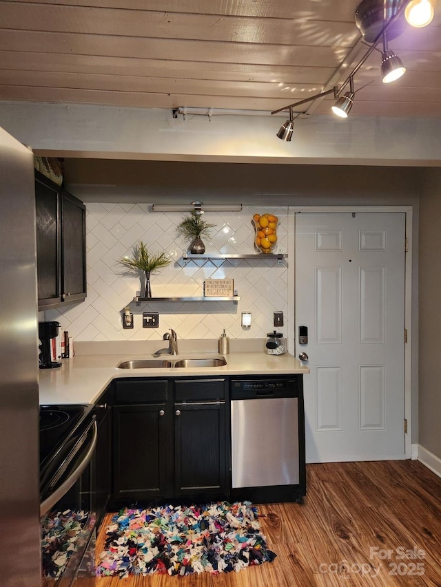 bar featuring sink, stainless steel appliances, light wood-type flooring, and tasteful backsplash