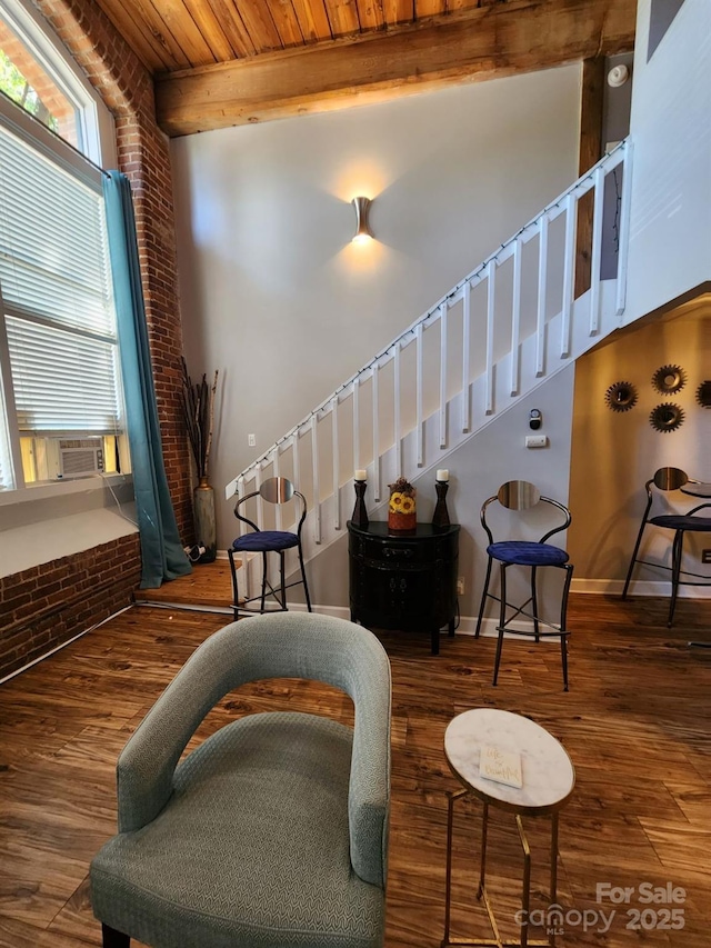 sitting room with brick wall, wood ceiling, beamed ceiling, and dark wood-type flooring