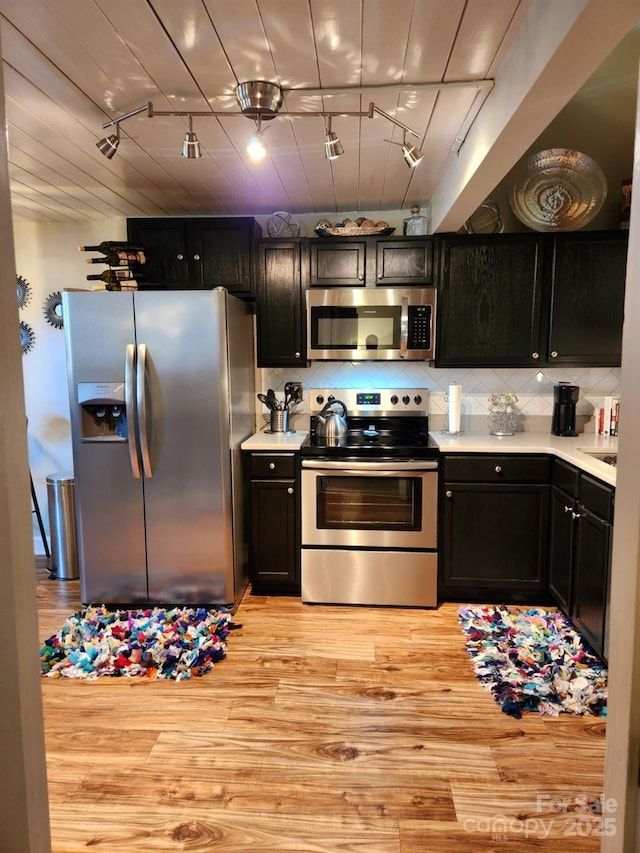 kitchen featuring light hardwood / wood-style floors, stainless steel appliances, track lighting, and decorative backsplash