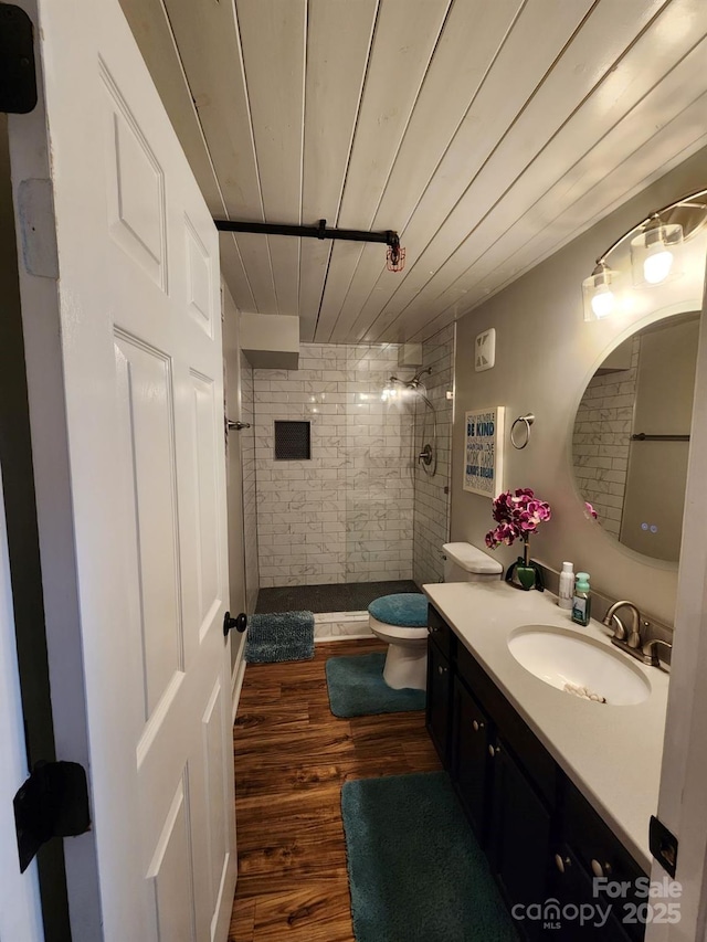 bathroom with toilet, a tile shower, vanity, and hardwood / wood-style flooring