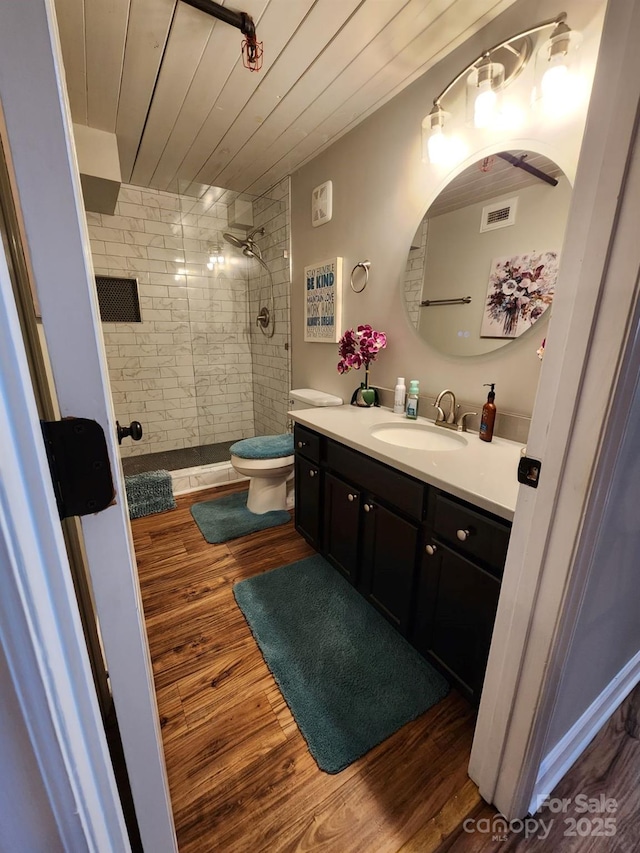 bathroom with wooden ceiling, tiled shower, hardwood / wood-style floors, toilet, and vanity