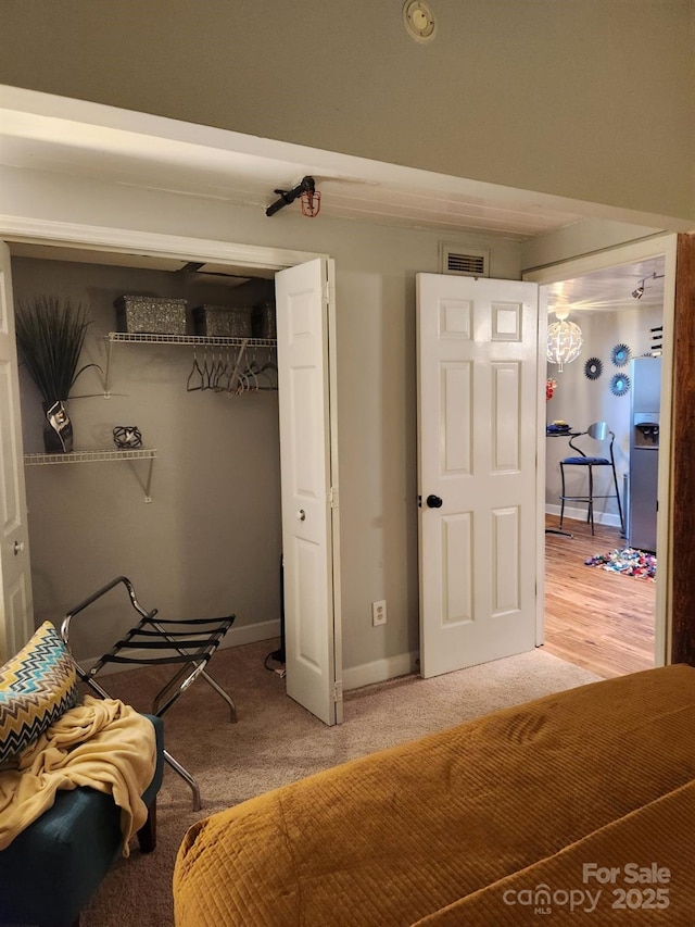 bedroom with a closet, carpet, and stainless steel refrigerator with ice dispenser