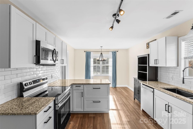 kitchen featuring sink, backsplash, white cabinets, and appliances with stainless steel finishes