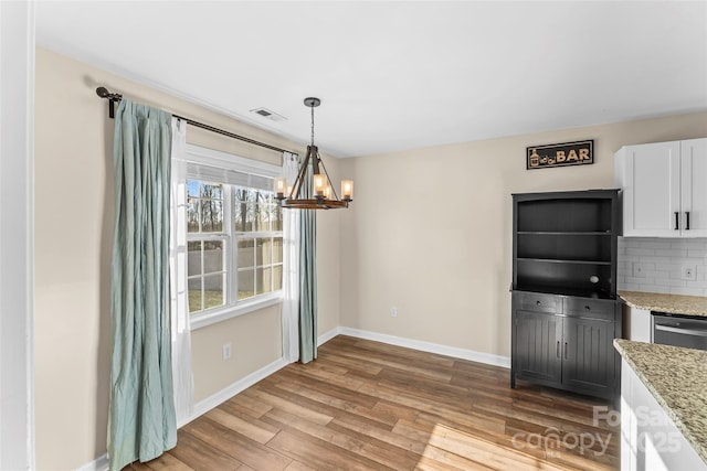 unfurnished dining area with wood-type flooring and a chandelier