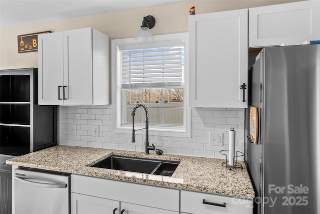 kitchen with stainless steel appliances, sink, white cabinets, and backsplash