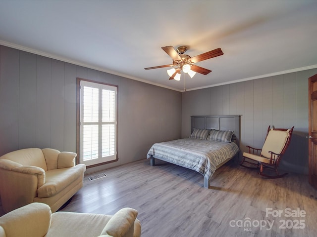 bedroom featuring ornamental molding, light hardwood / wood-style floors, and ceiling fan