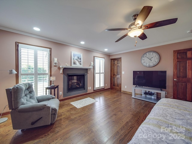 living room with dark wood-type flooring, ornamental molding, plenty of natural light, and ceiling fan