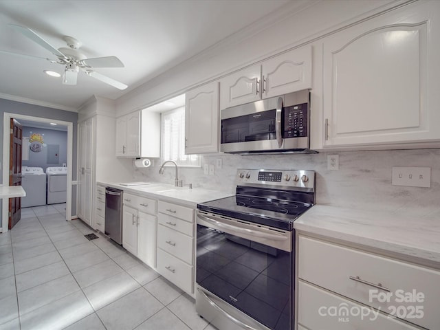 kitchen featuring sink, white cabinetry, appliances with stainless steel finishes, washing machine and dryer, and backsplash