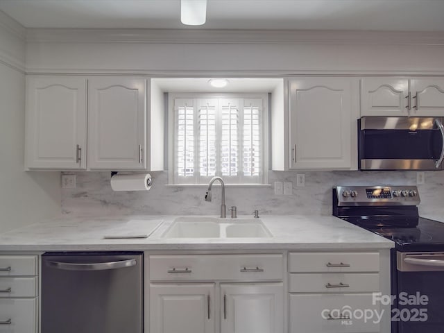 kitchen with tasteful backsplash, white cabinetry, appliances with stainless steel finishes, and sink