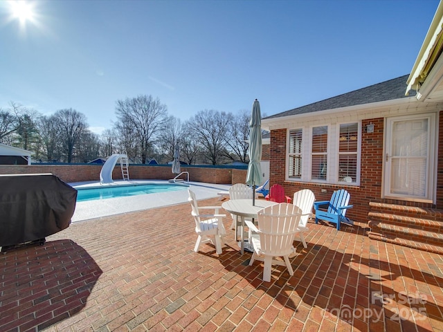 view of swimming pool with a grill, a water slide, and a patio