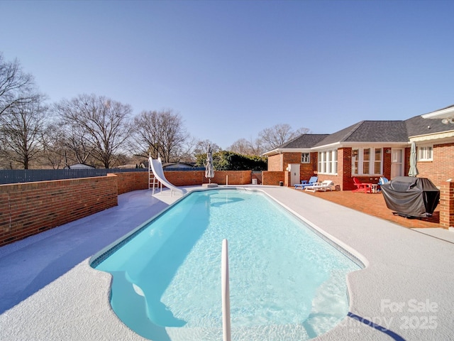 view of swimming pool with a water slide, grilling area, and a patio area