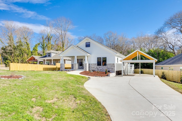 view of front of house with a porch, concrete driveway, fence, stone siding, and a front lawn