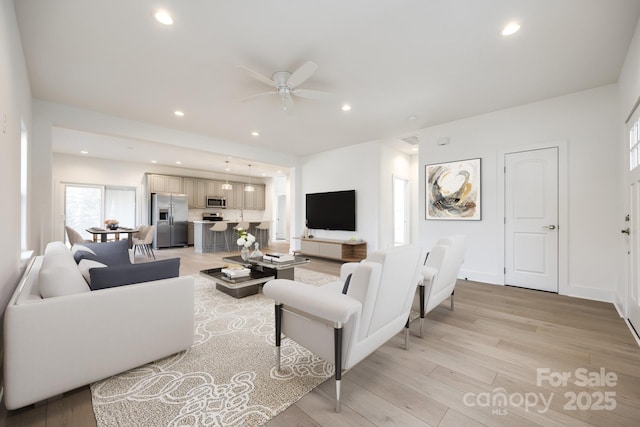 living room with baseboards, recessed lighting, a ceiling fan, and light wood-style floors