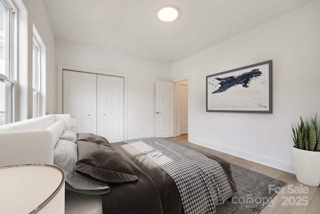 bedroom with light wood-style floors, baseboards, and a closet