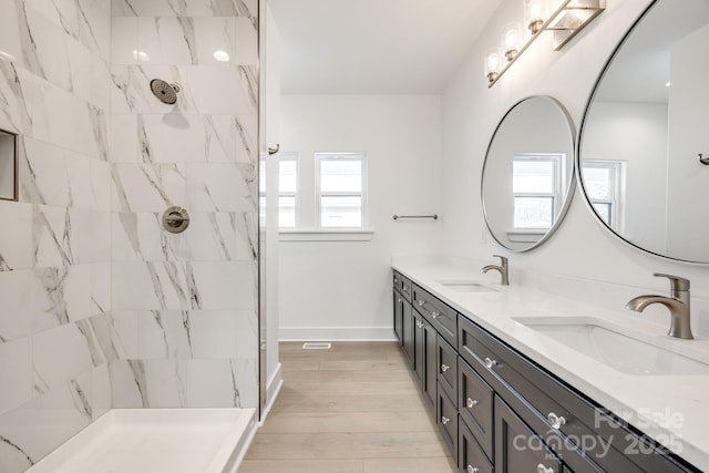 full bathroom featuring double vanity, a sink, and tiled shower