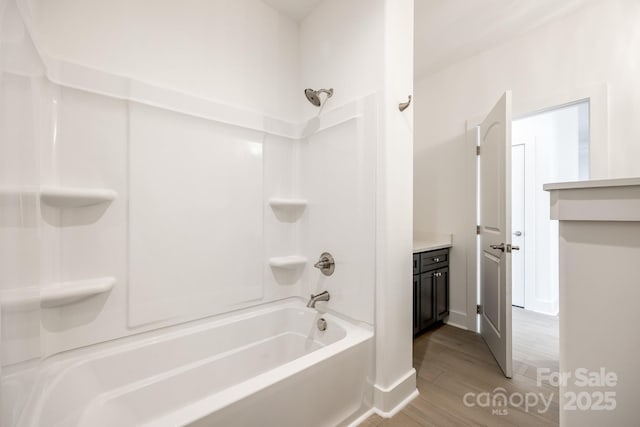 bathroom featuring vanity, wood finished floors, and bathing tub / shower combination