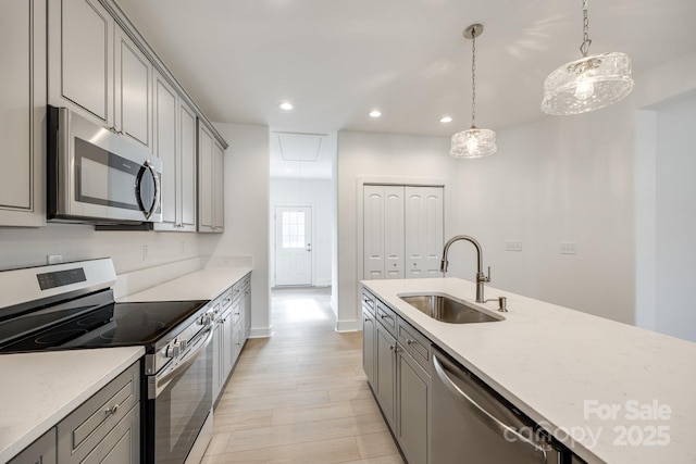 kitchen with decorative light fixtures, recessed lighting, gray cabinets, appliances with stainless steel finishes, and a sink