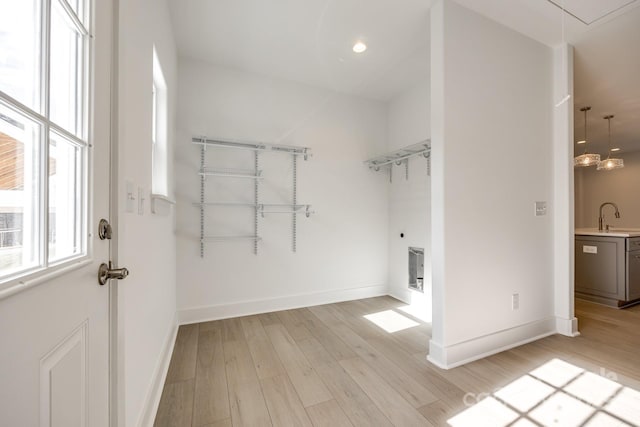 walk in closet featuring light wood finished floors, a sink, and attic access