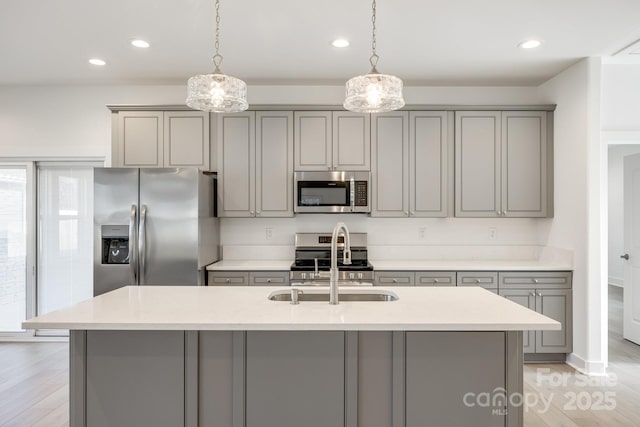 kitchen with a sink, appliances with stainless steel finishes, gray cabinets, and decorative light fixtures