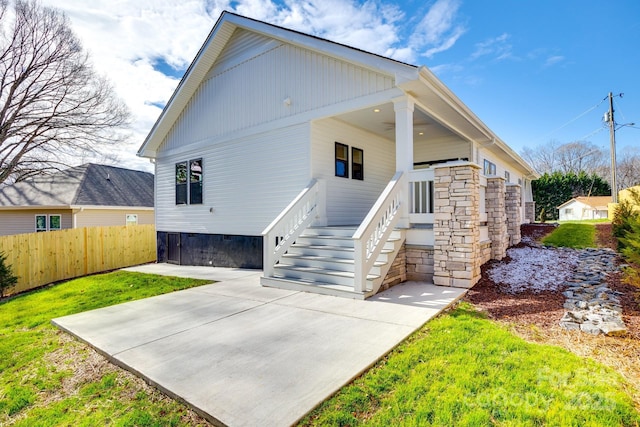 back of house with stairs, fence, and a yard