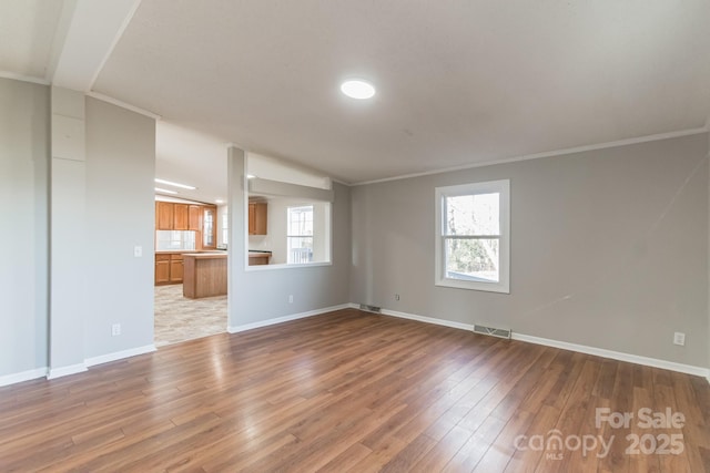 unfurnished living room featuring light hardwood / wood-style flooring, vaulted ceiling, and crown molding