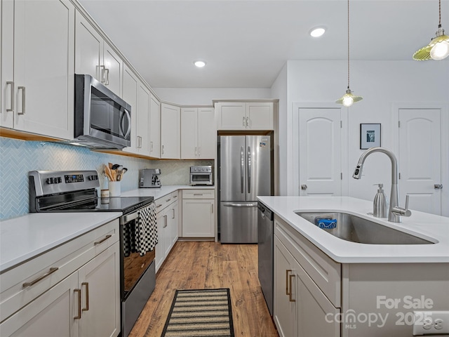 kitchen featuring stainless steel appliances, backsplash, hanging light fixtures, and sink