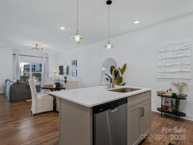 kitchen featuring dark hardwood / wood-style floors, pendant lighting, stainless steel dishwasher, a center island with sink, and sink