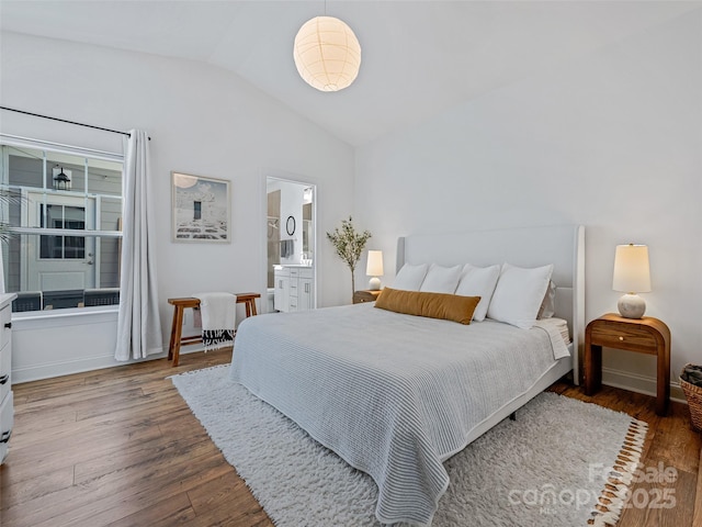 bedroom with vaulted ceiling, ensuite bathroom, and hardwood / wood-style floors