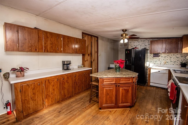 kitchen featuring white appliances, a kitchen bar, light wood-type flooring, ceiling fan, and a kitchen island