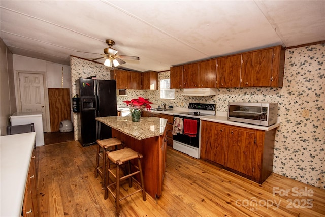 kitchen featuring black fridge with ice dispenser, white electric range, light hardwood / wood-style flooring, and a center island