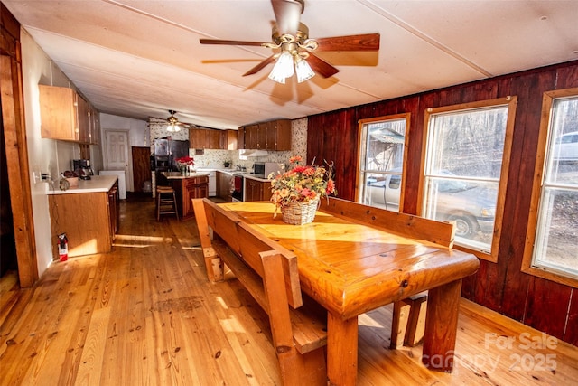 dining space featuring ceiling fan, light hardwood / wood-style flooring, lofted ceiling, and plenty of natural light