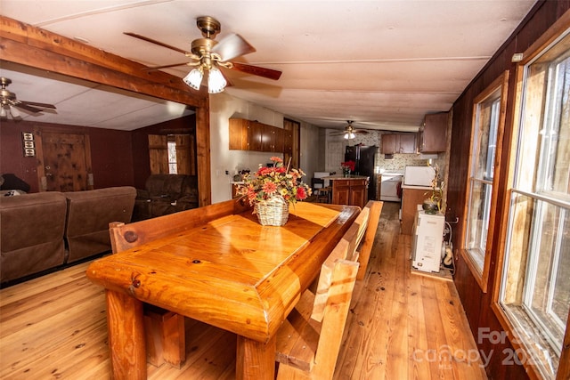 dining space featuring light wood-type flooring and lofted ceiling with beams