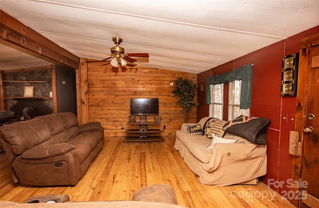 living room with lofted ceiling, wood walls, ceiling fan, and light hardwood / wood-style flooring