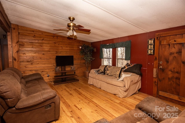 living room featuring ceiling fan, light hardwood / wood-style flooring, wooden walls, and lofted ceiling