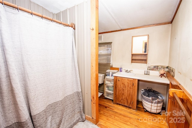 bathroom with toilet, vanity, ornamental molding, and hardwood / wood-style flooring