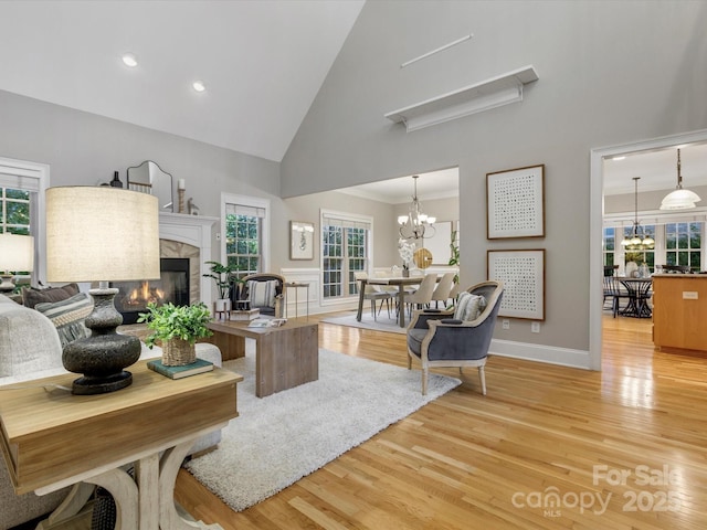 living room with a wealth of natural light, light hardwood / wood-style floors, a tile fireplace, and high vaulted ceiling